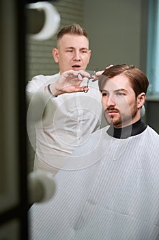 Caucasian barber cutting hair of his client indoors