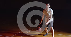 Caucasian basketball player dribbling a ball professional dark camera ray of light