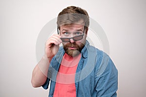 Caucasian, bearded man haughtily looks through lowered sunglasses. White background. photo