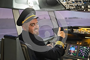 Caucasian bearded man smiling while driving a flight simulator. Pilot in the cockpit showing thumbs up.