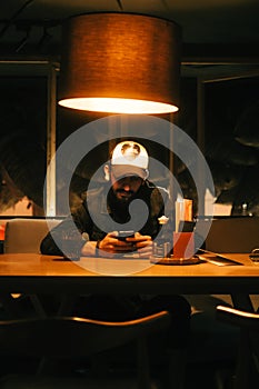 Caucasian bearded man using mobile phone in cafe at the night