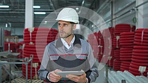 Caucasian bearded professional worker man in hard hat using tablet indoors