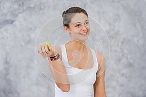 Caucasian beautiful healthy athletic sportive girl eat green apple after the training and looking at camera