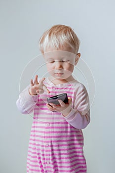 Caucasian blond baby with blue eyes making a call, playing with mobile cell phone