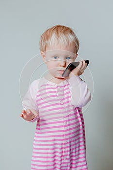 Caucasian blond baby with blue eyes talking over mobile cell phone