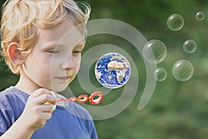 Caucasian blond boy is playing with soap bubbles