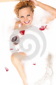 Caucasian Blond Female in Foamy Bathtub Filled with Flowery Petals Relaxing