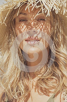 Caucasian blond woman wearing straw hat on a summer day, beach fashion style