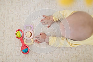 Caucasian blonde baby five months old lying on bed at home. Kid wearing cute clothing trendy colors: ultimate gray and