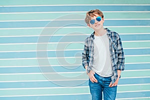 Caucasian blonde hair 12 year old teenager boy Fashion portrait dressed white t-shirt with checkered shirt in blue sunglasses with