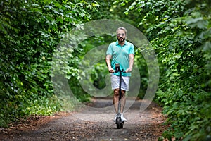 Caucasian blonde man riding electric scooter in park