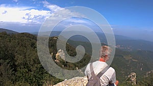 Caucasian blonde tourist man sitting on the rock in mountain Montseny in Spain over the valley with spectacular vista
