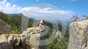 Caucasian blonde tourist man sitting on the rock in mountain Montseny in Spain over the valley with spectacular vista