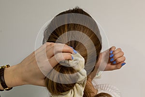 Caucasian blonde woman making a bun on a bottom of her head.