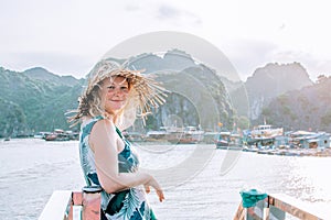Caucasian blonde woman in a straw hat enjoying the boat ride at Lan Ha Bay, Cat Ba island, Vietnam