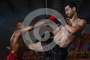 Caucasian boxer making kick in defense to african american boxer who making yap punce in kick boxing or muay thai fight match, photo