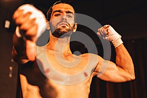 Caucasian boxer punch his bare fist and wrap posing. Impetus