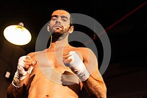 Caucasian boxer punch his bare fist and wrap posing. Impetus