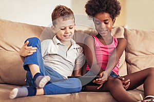 Caucasian boy and African American girl at home using tablet