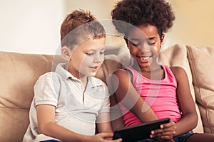 Caucasian boy and African American girl using tablet.