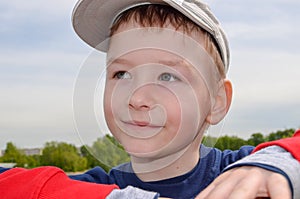 caucasian boy in a baseball cap smiles and dreams looks into the distance green park