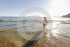 A boy standing in the shallows at the beach