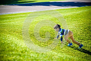 Caucasian boy climbs up on fresh green grass meadow, happy kids enjoying peaceful summer weekend outdoors. Friendship relaxation