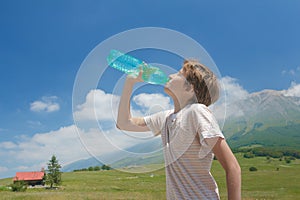Caucasian boy drinking clear water from battle in his hands high in Alps