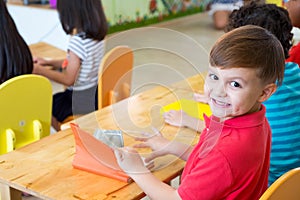 Caucasian boy ethnicity kid smiling in classroom with friends in