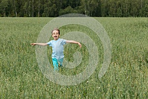 Caucasian boy on the field with a oats is running with his arms outstretched.