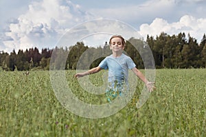 Caucasian boy on the field with a oats is running with his arms outstretched.