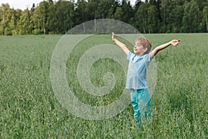Caucasian boy on the field with a oats stands with his arms outstretched. Happy child