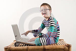 A Caucasian boy with glasses tries to work with a computer and the Internet. The guy gets vivid emotions.