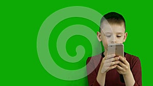 A Caucasian boy on a green background communicates with his mom on a Samrtphone. Children and communications. . Chroma