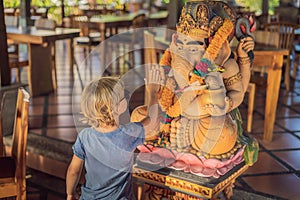 Caucasian boy high-five Ganesha. Meeting Western and Eastern culture concept. oriental and occidental. Traveling to Asia with chi photo