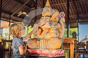 Caucasian boy high-five Ganesha. Meeting Western and Eastern culture concept. oriental and occidental. Traveling to Asia photo