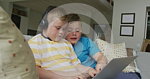 Caucasian boy with his brother sitting in living room and using laptop