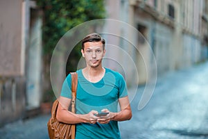 Caucasian boy is holding cellphone outdoors on the street. Man using mobile smartphone.