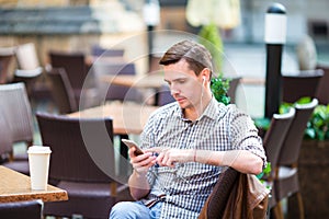 Caucasian boy is holding cellphone outdoors on the street. Man using mobile smartphone.