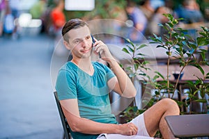 Caucasian boy is holding cellphone outdoors on the street. Man using mobile smartphone.