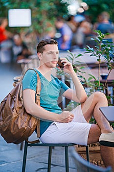 Caucasian boy is holding cellphone outdoors on the street. Man using mobile smartphone.