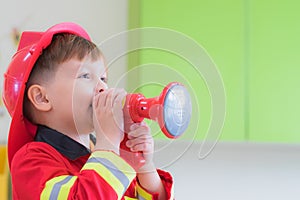 Caucasian boy kid dress up to fireman and use speaker at roll pl
