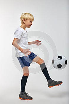 Caucasian boy kneeing a soccer ball isolated in studio