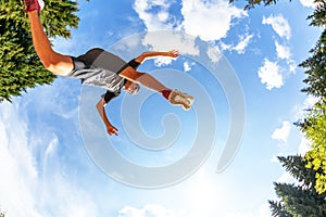 Caucasian boy makes a jump in a mountain meadow. View from Below