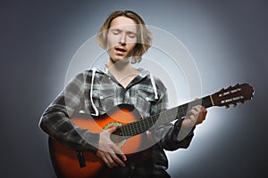 Caucasian boy playing on acoustic guitar. Teenager with classic wooden guitar