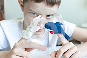 A caucasian boy playing different roles by using finger puppets, toys for expressing his emotions, agression, fear and freandship