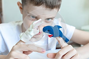 A caucasian boy playing different roles by using finger puppets, toys for expressing his emotions, agression, fear and freandship