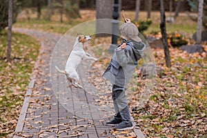 Caucasian boy playing with a dog for a walk in the autumn park.