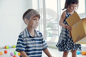 A Caucasian boy plays colorful balls with his little sister.