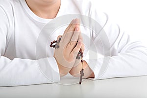 Caucasian boy praying holds Rosary with both hands